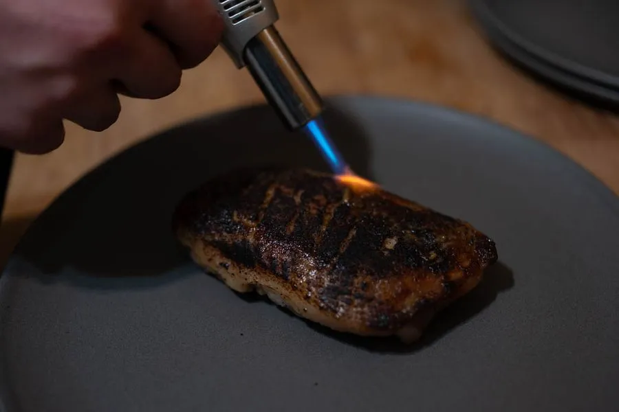 Duck breast rendering skin-side down in a cast iron pan, golden fat pooling around the edges