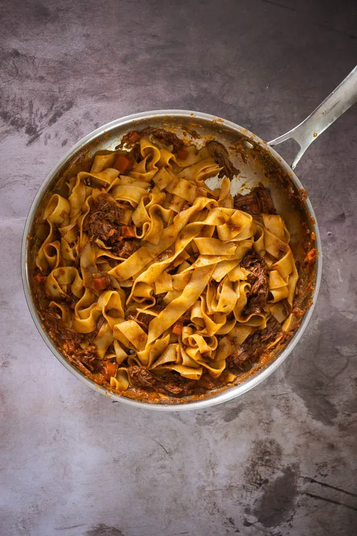 Pappardelle fully coated in rich beef ragu, a cloud of freshly grated Parmesan melting into the glossy sauce