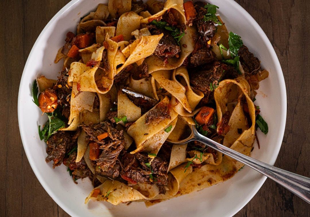 Wide pappardelle ribbons coated in rich slow-cooked beef ragu topped with freshly grated Parmesan cheese