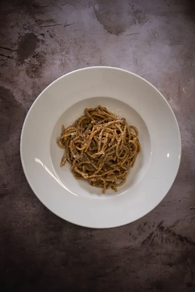 Creamy Pecorino Romano cheese sauce coating each strand of spaghetti in the pan