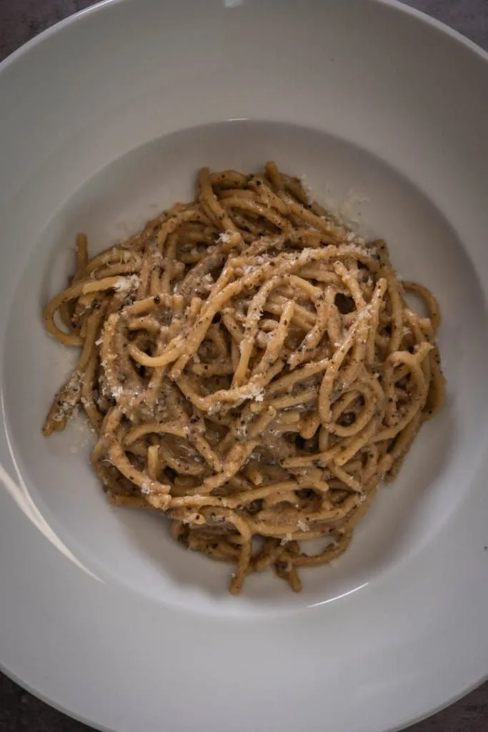 Perfectly plated cacio e pepe, spaghetti twirled into a nest with a generous crown of cracked black pepper and snowy Pecorino