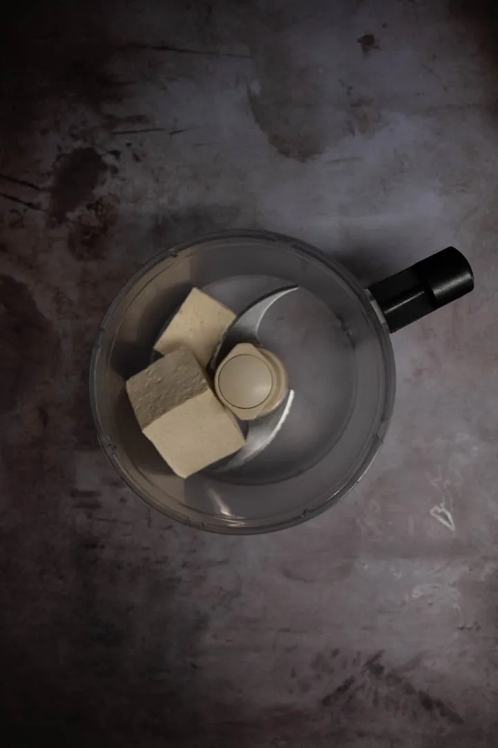 Silken tofu being blended smooth in a food processor, pale and creamy