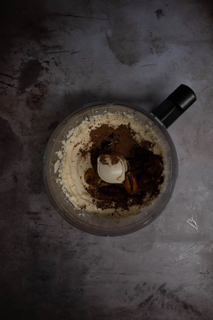Glossy chocolate tofu mixture in a blender after adding cacao powder, vanilla, and olive oil