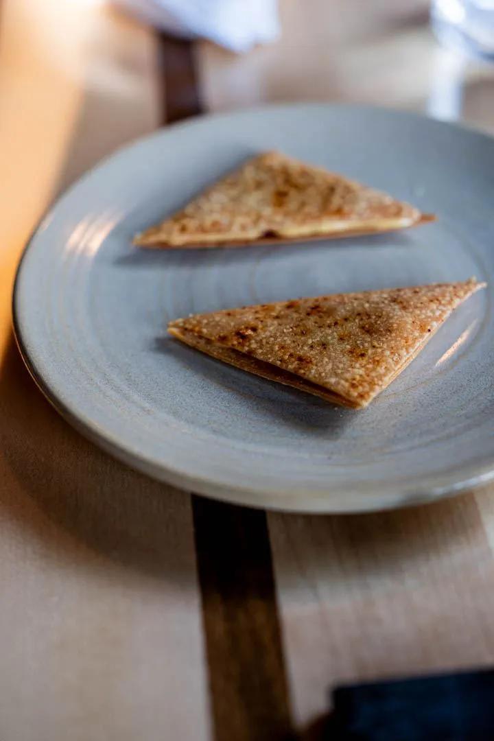 Amuse-bouche and small between-course bites at Hoogan et Beaufort Montreal, delicate one-bite preparations on slate, showing the kitchen's attention to detail