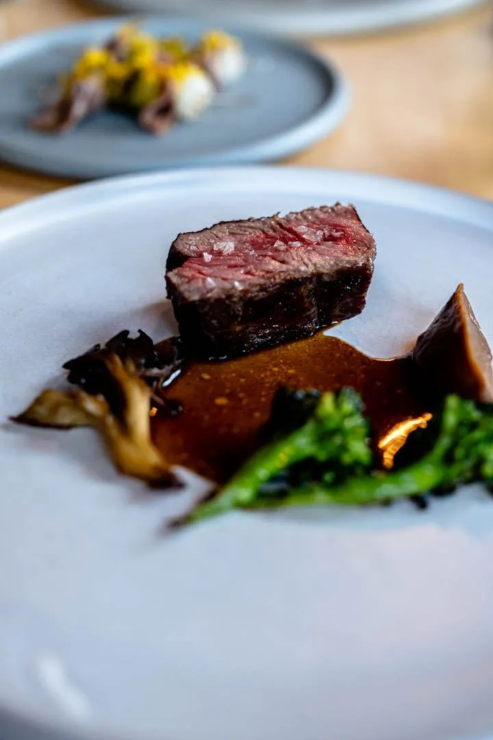 Beef with maitake mushrooms and black cardamom at Hoogan et Beaufort Montreal, a beautifully plated main course with rich dark jus and precise garnish