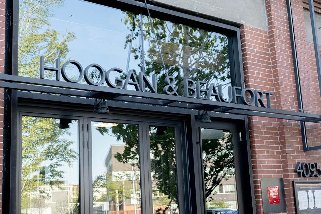 Warm, intimate dining room at Hoogan et Beaufort Montreal with pendant lights and live-fire kitchen visible in the background
