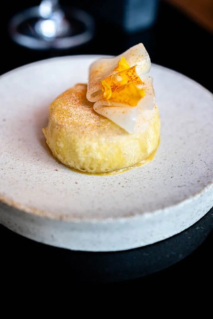 First course at Île Flottante Montreal tasting menu, precisely plated seasonal ingredients on fine ceramic