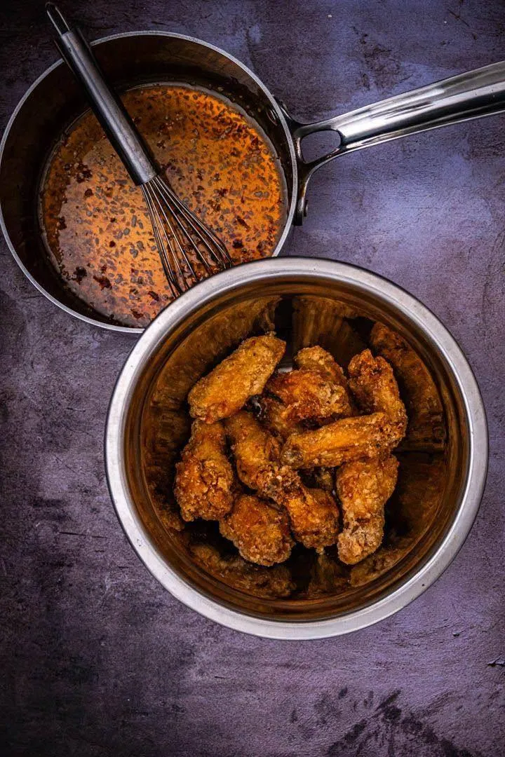 Vietnamese fish sauce wings tossed in glossy caramel glaze, glistening and coated with crispy fried garlic pieces in a large bowl