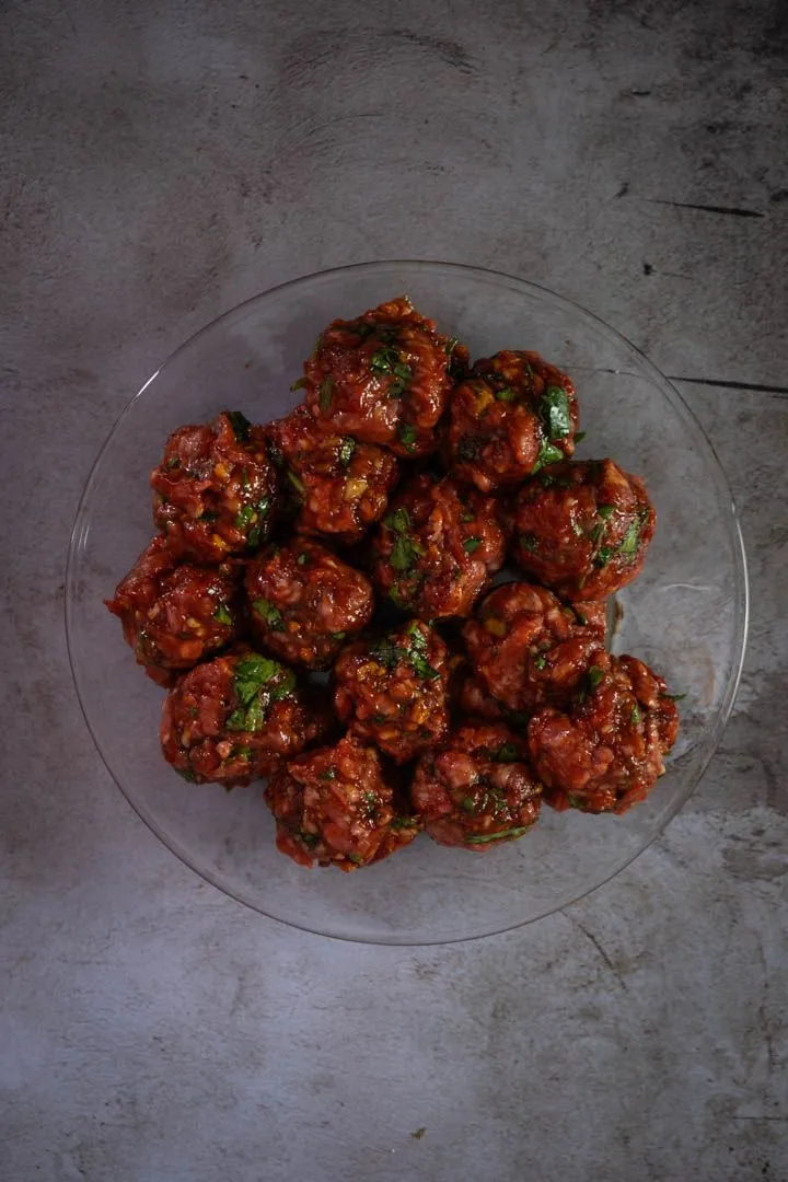 Lamb meatballs browning in a hot skillet with golden crust forming on the bottom