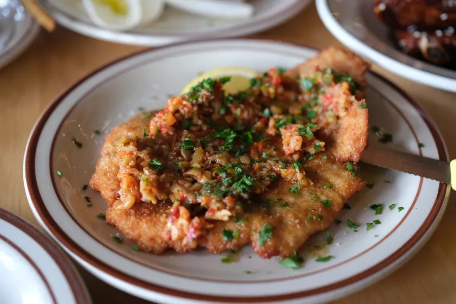 Schnitzel bomba avec panure dorée et croustillante garni de relish bomba épicée et d'herbes fraîches au McKiernan
