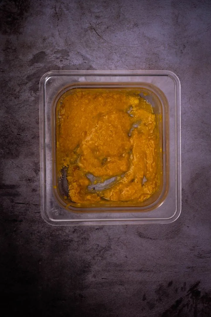 Golden egg yolk, cheese, and miso mixture whisked smooth in a glass container, ready to toss with the noodles