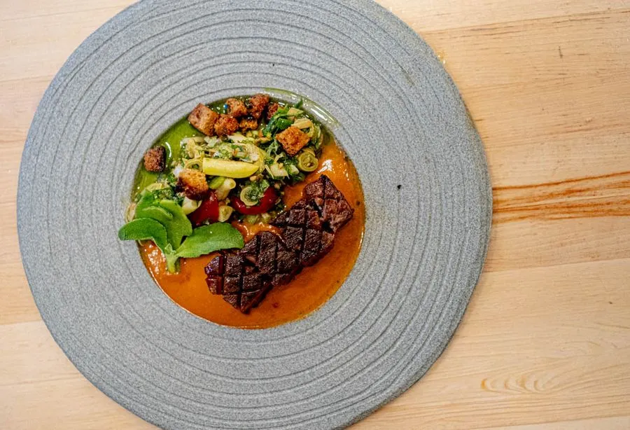 Beef tongue with tomato, Japanese knotweed, and sauce vierge at Othym Montreal, silky and tender with bright acidic lift from the herb-oil sauce