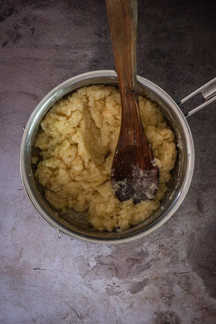 Hot choux dough transferred into a food processor bowl, ready for eggs to be added