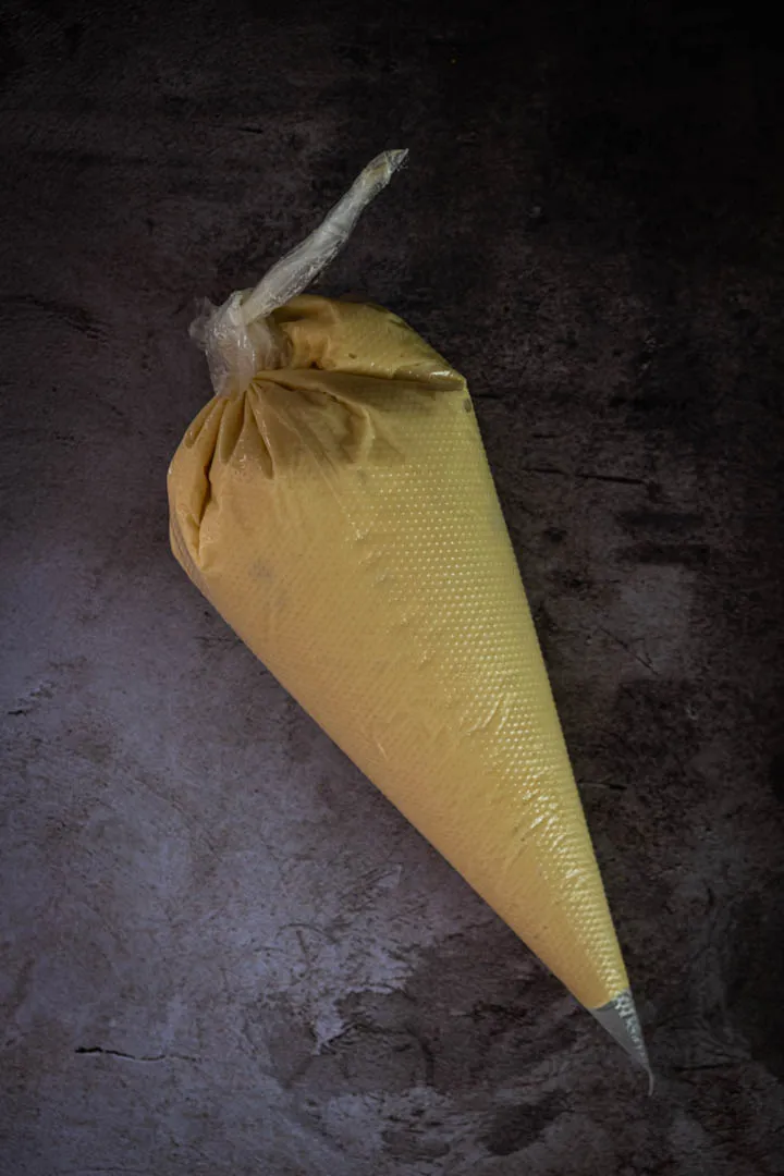 Choux dough loaded into a piping bag fitted with a round tip, ready to pipe onto a baking sheet