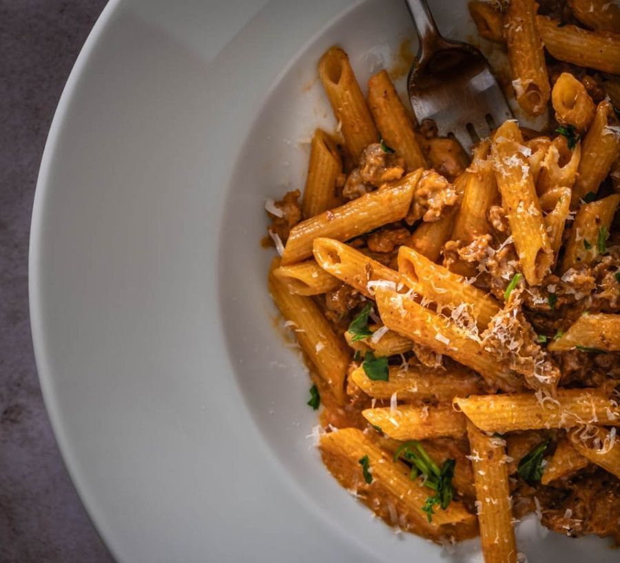 Finished penne alla vodka with Italian sausage garnished with fresh herbs and Parmesan