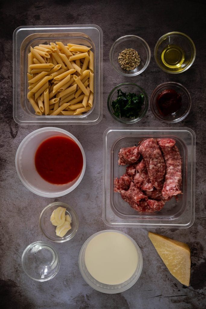 Ingredients for penne alla vodka with sausages including pasta, cream, tomatoes, vodka, and Italian sausage