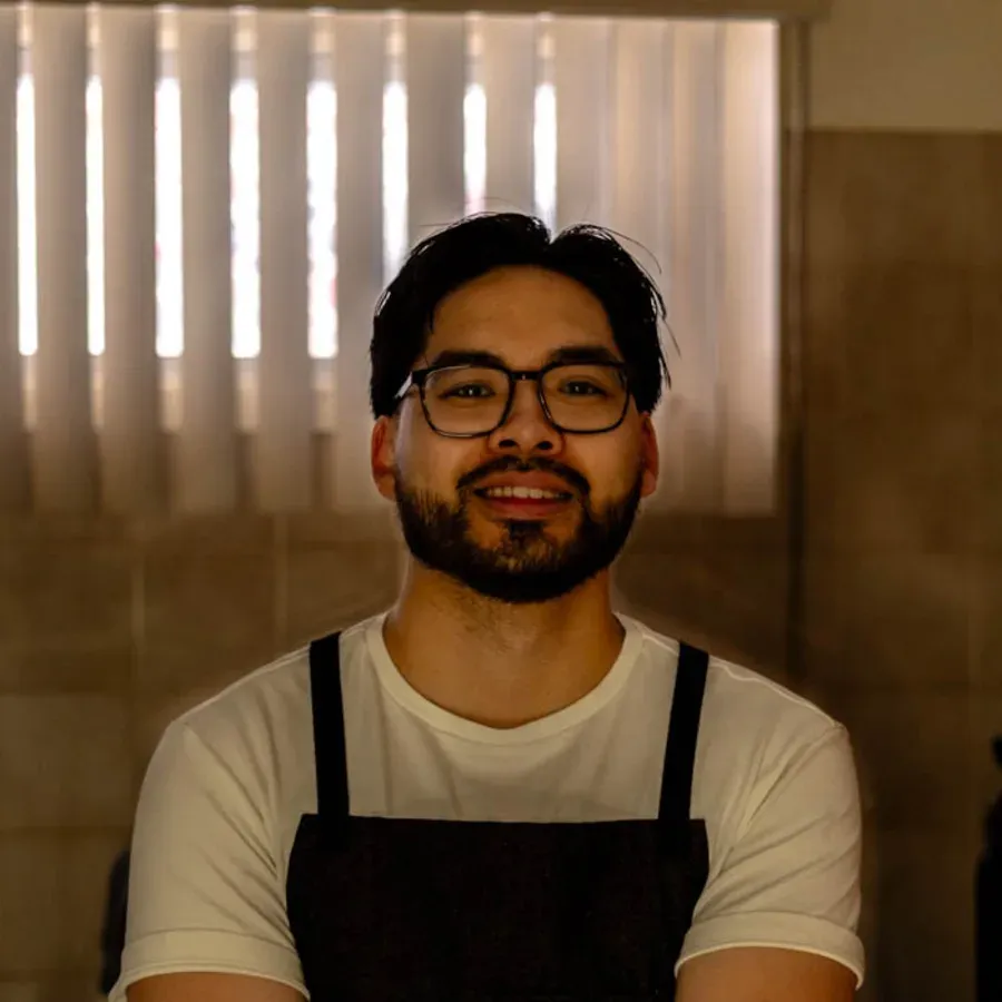 Victor Vu, home cook and creator of Date My Dish, standing in his Montreal kitchen wearing an apron with arms crossed