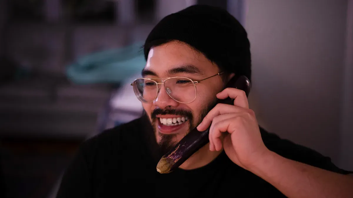 Victor Vu laughing while holding an eggplant like a phone in his Montreal kitchen