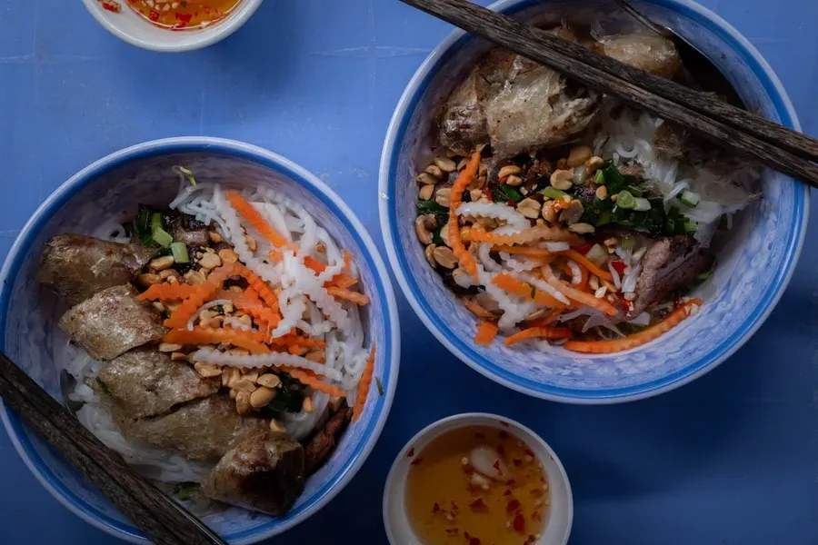 Vietnamese do chua pickled vegetables served alongside grilled pork and steamed rice, showing the classic Vietnamese pairing