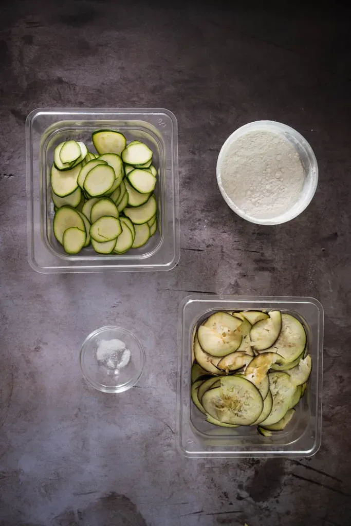 Ingredients for vegetable chips including zucchini, eggplant, canola oil, flour, and sea salt