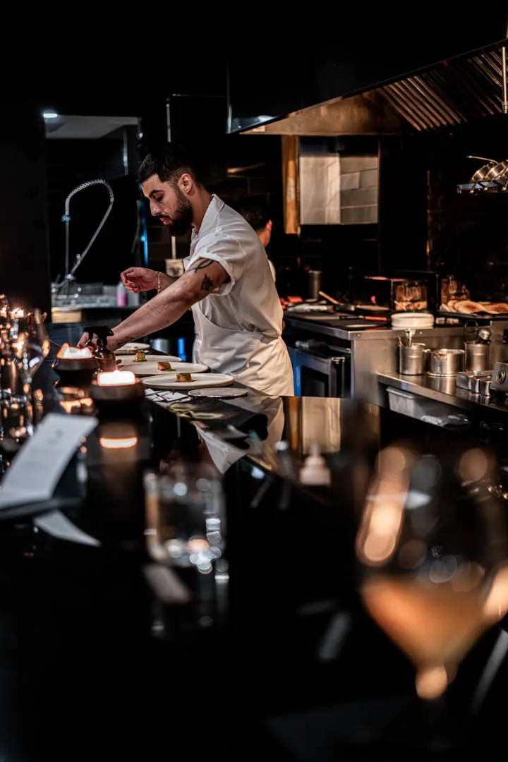 A cook plating at the pass, seen from the counter