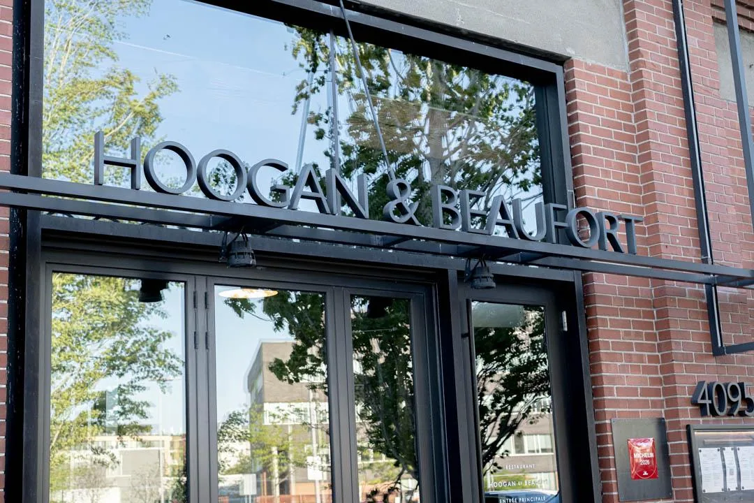 Warm, intimate dining room at Hoogan et Beaufort Montreal with pendant lights and live-fire kitchen visible in the background